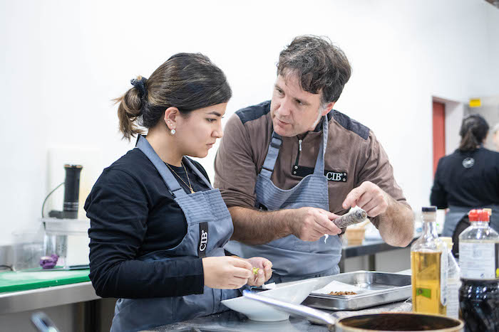 Tecnología Alumno y profesor trabajando técnicas culinarias